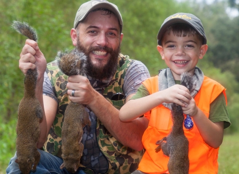 Man and young boy holding squirrels