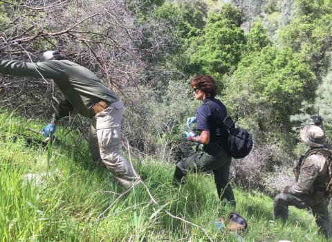 Lori Choquette and team walking uphill in a grassy area.