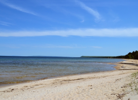 Calm water washes up on sandy beach.