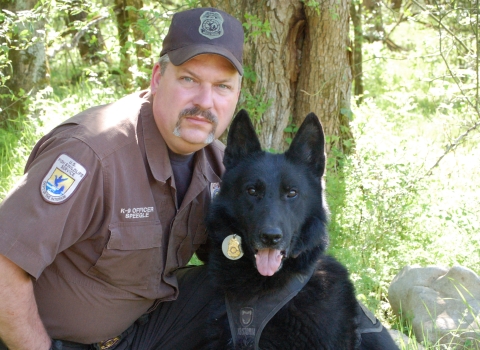 man in uniform with black dog 