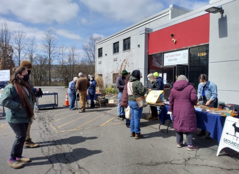 Community members standing in front of building collecting seeds. 