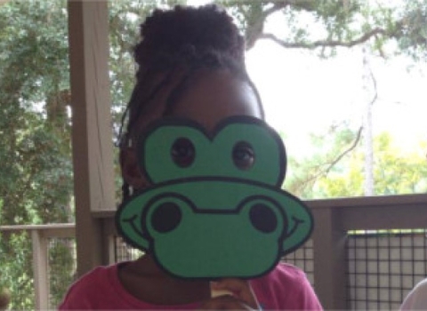 Two kids wearing alligator masks they made during an education program.