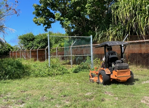 Maintenance worker mowing Refuge property