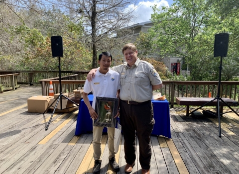 A volunteer stands alongside the project leader on a wooden pavilion.