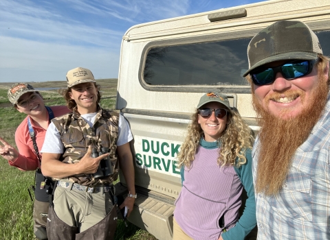 four people standing in front of a truck 