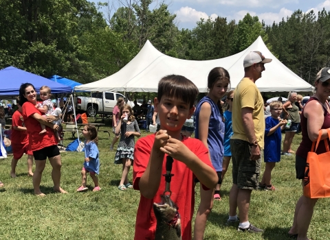 Boy holding large rainbow trout with hand scale