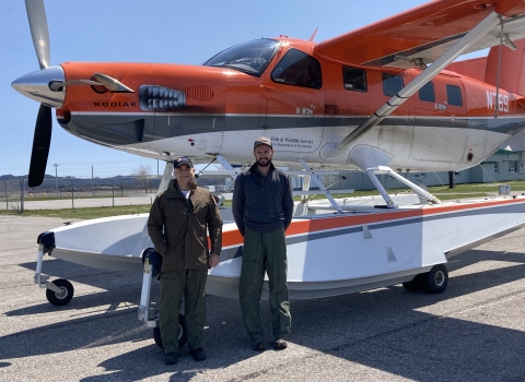 two people standing in front of an airplane