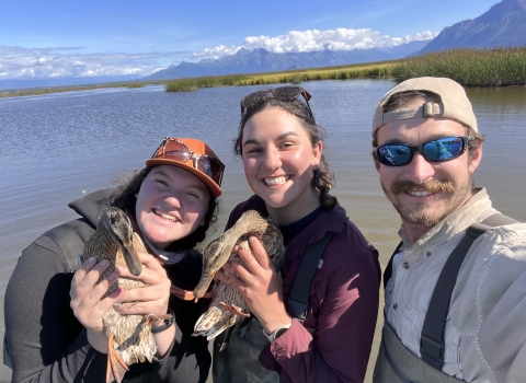 three people smiling, 2 are holding ducks