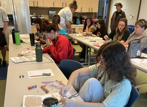 A group of people at tables working on a craft project.