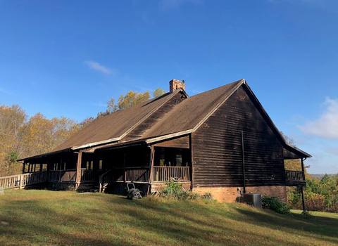 a brown, wooden building on a grassy hill