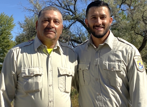 Two men in uniform smiling in an outdoor setting