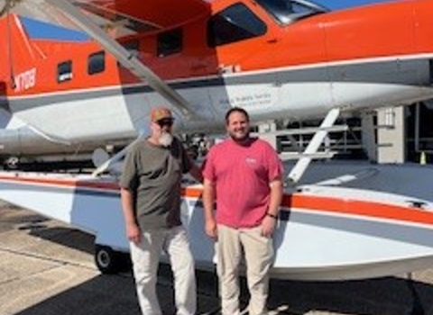 two people standing in front of an airplane