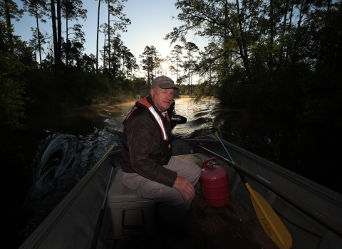 Larry Woodward pilots a boat into the Okefenokee Swamp in the early morning. He is the deputy manager of the Okefenokee National Wildlife Refuge.