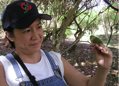 Marilet Zablan with bridled white-eye in a forest on Guam