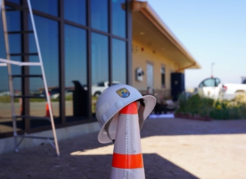 Foreground: USFWS Branded Helmet atop Hazard Cone. Background: Visitor Center of Rocky Mountain Arsenal National Wildlife Refuge